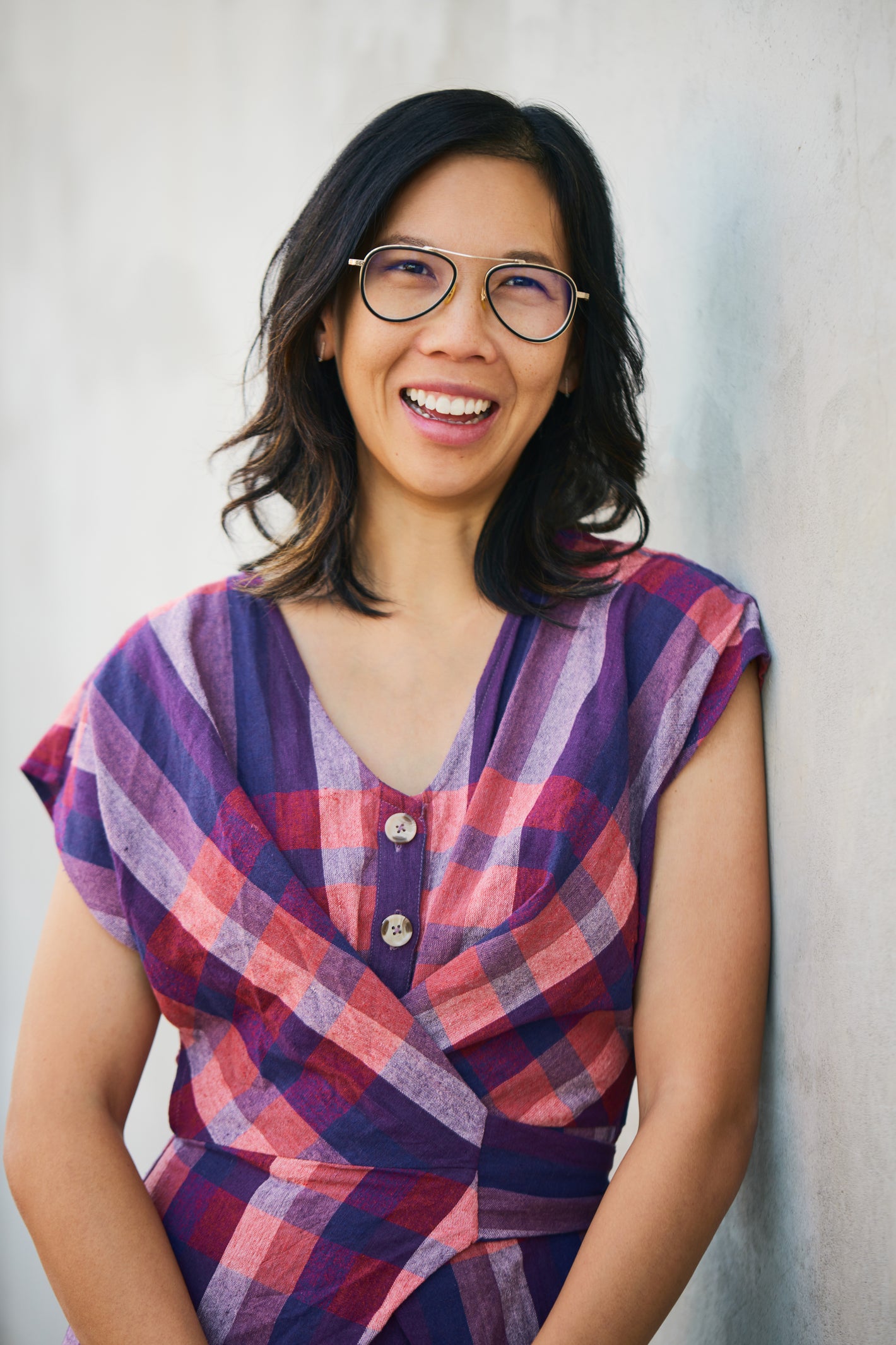 Woman wearing a colorful plaid shirt against a plain background